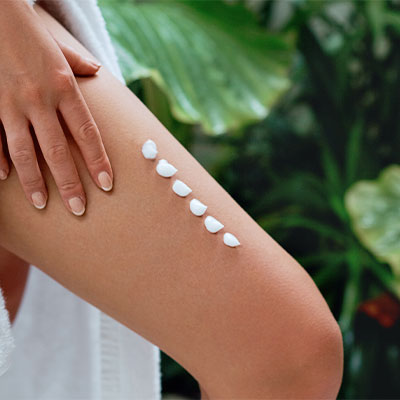 A woman's upper leg with dollops of Pevonia moisturizer.