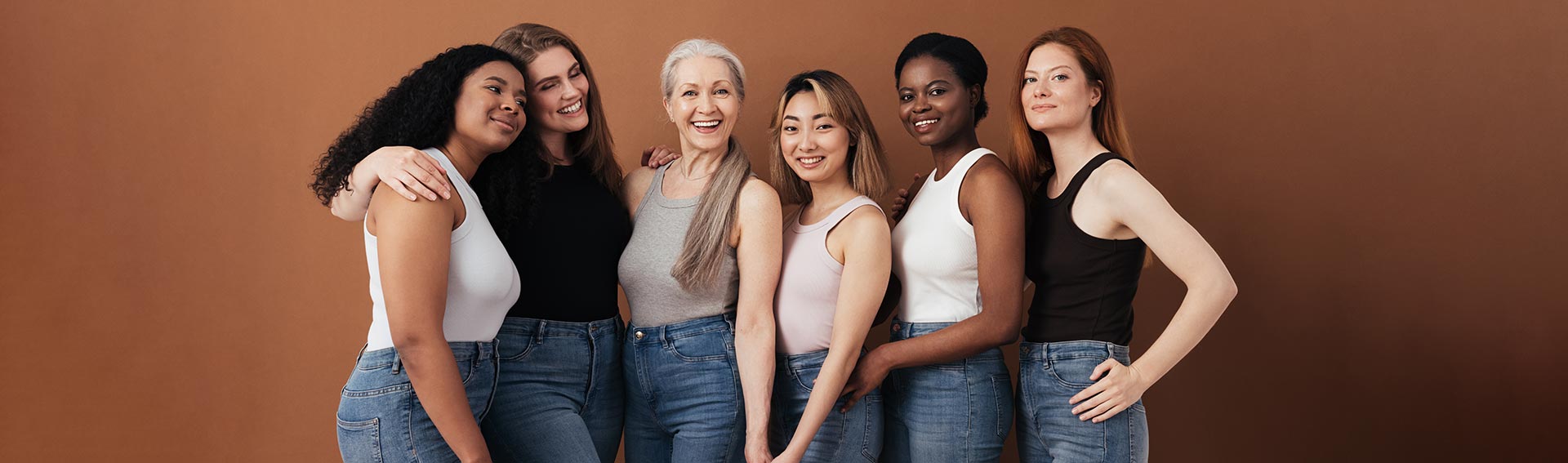 A group of women, all different ethnicities and ages, posing and smiling together.