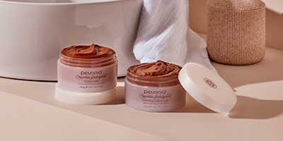 Pevonia Chocolate Indulgence products with their lids off near a bathroom sink.