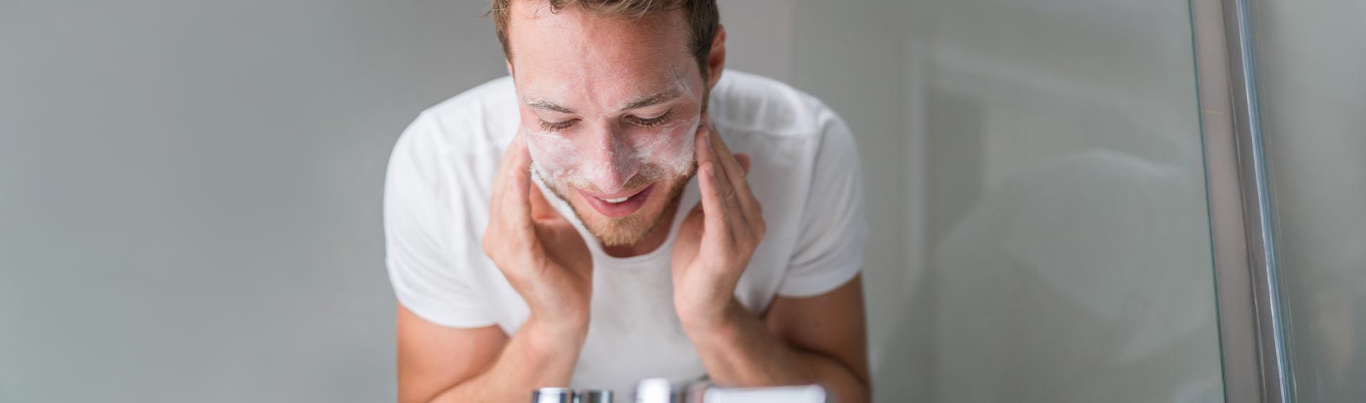 A man washing his face over the sink.