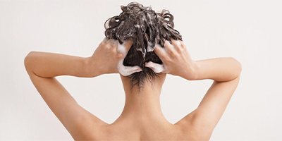 A woman washing her hair with Pevonia's Hair Energize Products.