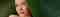 A woman's face in between large, tropical leaves.
